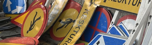 A pile of ro ad signs half-trashed and piled up on a building-site, to indicate the site is in construction.